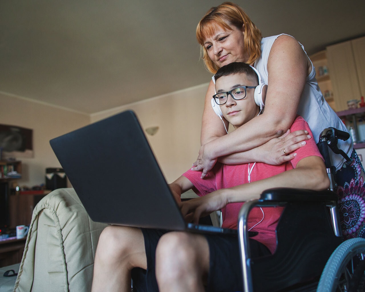 Teen son with disability and mum hugging