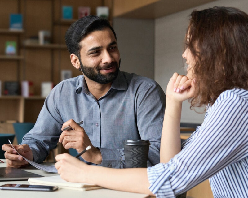 A man and a woman who are colleagues at work in discussion.