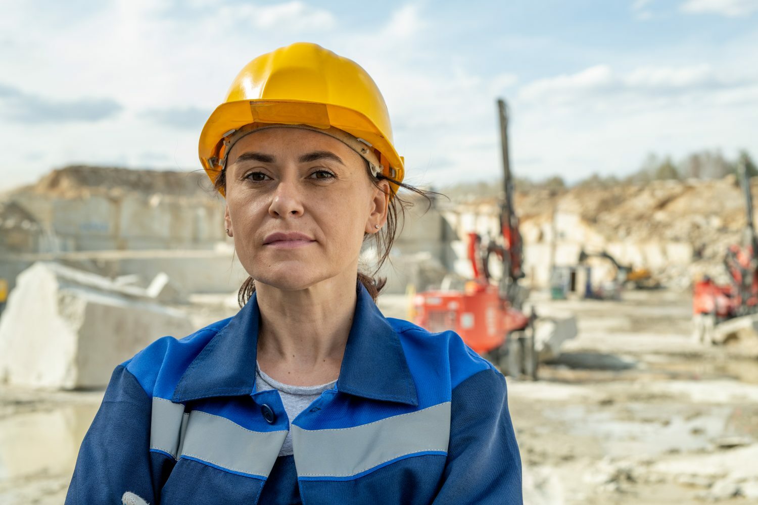 IStock 1330222733 e1668482678134 Pi A Female miner in hardhat looking at camera in a mining workplace setting